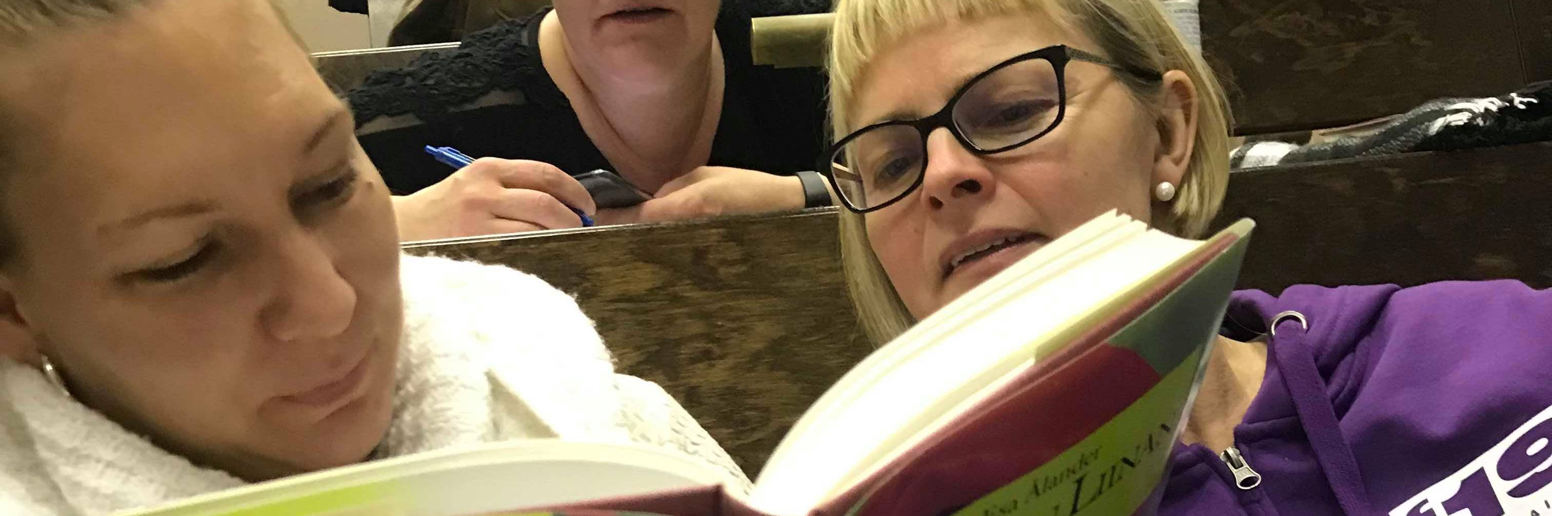 Kaksi henkilöä lukemassa Punaisen liinan lapset -kirjaa.